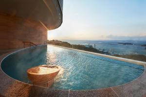 a swimming pool with a tub on the side of a building at Infinito Hotel and Spa in Shirahama