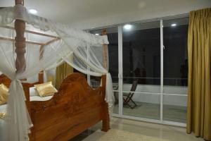 a bedroom with a canopy bed and a balcony at Tea Hills Bungalow in Hatton