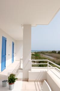 a white house with blue doors and a view of the ocean at La Dimora Salento in Carovigno