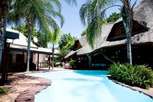 a resort with a swimming pool in front of a building at Dei Gratia Guest House in Musina