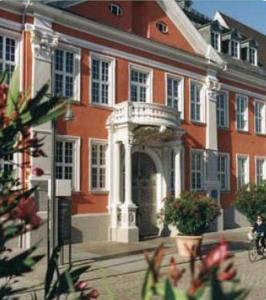 ein großes rotes Gebäude mit einem weißen Bogen davor in der Unterkunft Hotel-Pension Klaer in Speyer