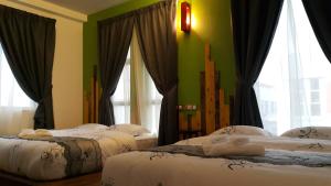 two beds in a room with green walls and windows at PI Grand Hotel in Sepang