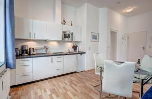 バンシンにあるVilla Frieda Wohnung 8の白いキャビネット、テーブルと椅子付きのキッチンが備わります。