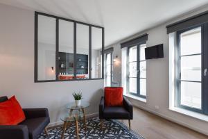 ein Wohnzimmer mit 2 Stühlen, einem Tisch und Fenstern in der Unterkunft Stay Appart Hotel Lille Centre in Lille