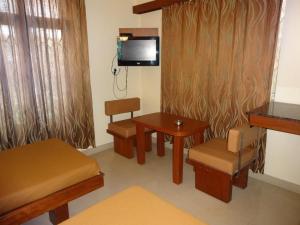 a room with a table and chairs and a tv at Sheetal Residency in Bangalore