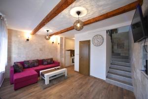 ein Wohnzimmer mit einem rosa Sofa und einem TV in der Unterkunft Villa Old Olive 2 in Budva
