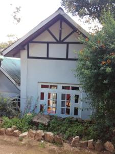 a white house with a window and a tree at Sincere Wilderness Home stay in Nuwara Eliya