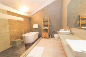 La salle de bains est pourvue d'une baignoire blanche et d'un lavabo. dans l'établissement The Elephant Stables, à Kandy