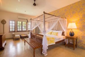 ein Schlafzimmer mit einem Himmelbett und einer Bank in der Unterkunft The Elephant Stables in Kandy