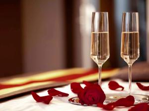 two champagne glasses on a table with red rose pedals at Stardust Rome Guest House in Rome