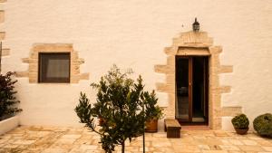 un bâtiment blanc avec une porte et quelques plantes dans l'établissement B&B Trulli Mansio, à Alberobello