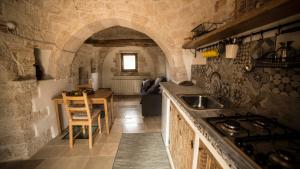 une cuisine avec un évier et une table dans une pièce dans l'établissement B&B Trulli Mansio, à Alberobello 11 autres photos