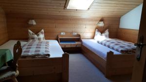 dwa łóżka w pokoju z drewnianymi ścianami w obiekcie Gasperlerhof w Neustift im Stubaital