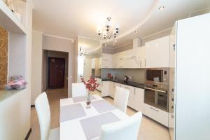 a white kitchen with a white table and white chairs at Apartment on Pritomskiy prospekt in Kemerovo