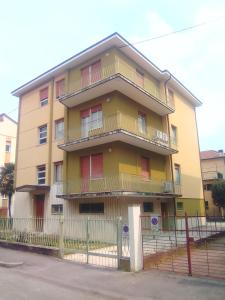 un bâtiment jaune avec balcon et clôture dans l'établissement Gardenia Guest House, à Forlì