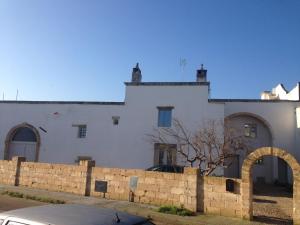 a white building with a stone fence in front of it at Antica e luminosa masseria in Lequile