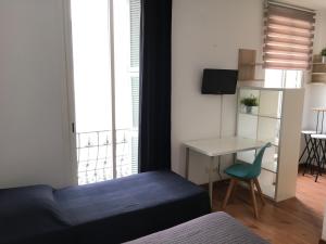 a bedroom with a bed and a table and a desk at Hôtel du Petit Louvre in Nice
