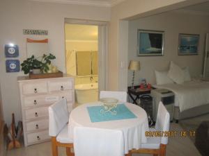 une chambre avec un lit, une table et des chaises dans l'établissement Twilight Cottage, à Plettenberg Bay