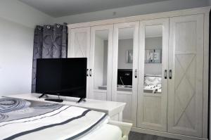 a bedroom with a bed and a tv and cabinets at Dieken's Huus in Wangerland