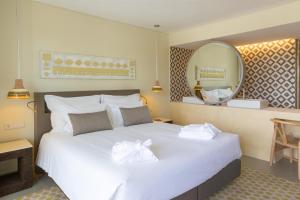 a hotel room with a large bed and a large mirror at OZADI Tavira Hotel in Tavira