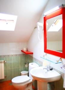 y baño con aseo blanco y espejo rojo. en Alojamiento en entorno rural Los Trobos, en Villar de Otero