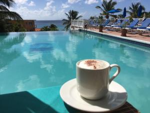 a cup of coffee sitting on a table next to a swimming pool at La Vista Resort in Simpson Bay