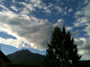 a cloudy sky with a tree and a mountain at Hotel Adler in Menaggio