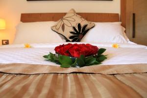 a bouquet of red roses on a bed at Sofi Apartment at Jayakarta Residence in Legian