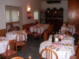 un comedor con mesas blancas y sillas con comida en Albergo Aquila, en Lido di Jesolo