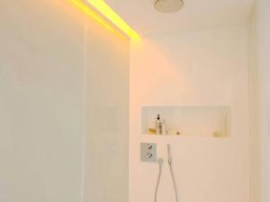 a white bathroom with a shower with a light on the ceiling at Minimalistic In Premium Location in Brussels