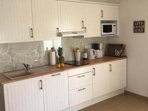 cocina con armarios blancos, fregadero y microondas en SEASIDE APARTMENTS - SANDY GOLD en Eckernförde