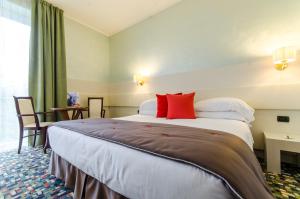 a hotel room with a bed, chair, and nightstand at Hotel Ovidius in Sulmona