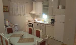 Una cocina con gabinetes blancos y una mesa con sillas. en Apartment Viki, en Makarska