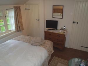 Dormitorio con cama y tocador con TV en Kipps Farm, en Great Torrington