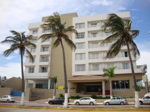 a large white building with palm trees in front of it at Balaju Hotel & Suites in Veracruz