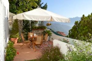 a patio with an umbrella and a table and chairs at Villa Valeria in Ravello