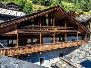 - un bâtiment avec un balcon en bois sur le côté dans l'établissement Chalet Geneviève, à Sainte-Foy-Tarentaise