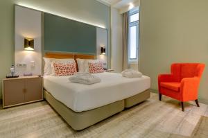 a bedroom with a large bed and a red chair at Vincci Baixa in Lisbon
