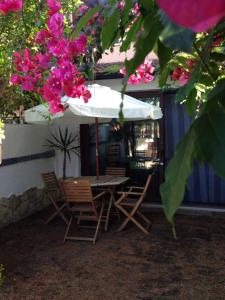 een tafel en stoelen met een witte parasol en roze bloemen bij Villa stella di mare in Capitana