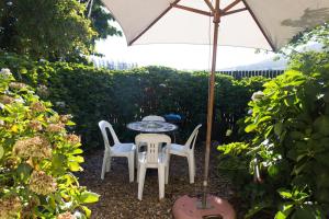 a table and chairs under an umbrella in a garden at White Bridge Farm Accommodation in Wolseley