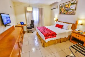 a hotel room with a bed and a desk and a television at Sun Valley Marília by Atlantica in Marília
