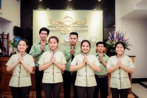 un grupo de personas de pie en una habitación con sus corbatas en NKS Hotel, en Phnom Penh