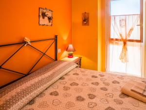 een slaapkamer met oranje muren en een bed met een raam bij Il Fontanile in Marina di Grosseto