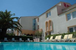 a hotel with a swimming pool with chairs and a building at Hôtel Azur in Cap d'Agde