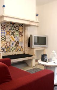 a living room with a fireplace with a tv on a wall at Origens Hostel in Sines