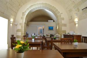 ein Restaurant mit Tischen und Stühlen und einem Torbogen in der Unterkunft Masseria San Cosimo in Carpignano Salentino