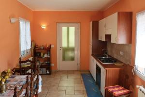 una cucina con pareti arancioni, tavolo e porta di Casa Delle Olive a Dolceacqua