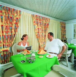 Ein Mann und eine Frau sitzen an einem Tisch in der Unterkunft Coral Sands Beach Resort in Bridgetown