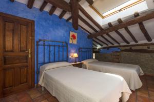 two beds in a room with blue walls at Casa Trallero in Almazorre