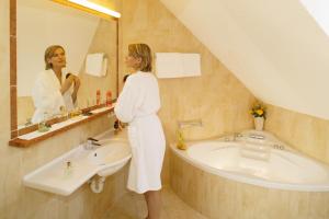a woman standing in a bathroom looking at herself in the mirror at Ferienwohnungen Kurhotel Eichinger in Bad Wörishofen +13 photos
